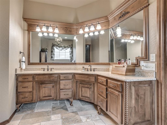 bathroom with stone tile flooring, double vanity, an inviting chandelier, and a sink