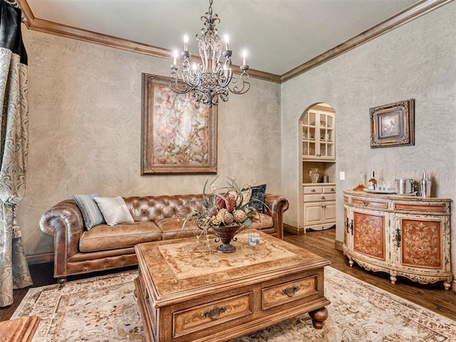 living area with a notable chandelier, wood finished floors, arched walkways, and ornamental molding