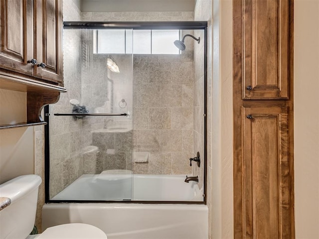 bathroom with combined bath / shower with glass door and toilet