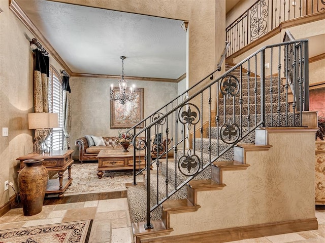 stairway with ornamental molding, stone tile flooring, baseboards, a chandelier, and a textured wall