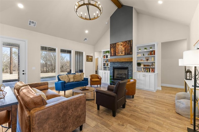 living area with visible vents, a chandelier, beam ceiling, a tile fireplace, and light wood-style floors