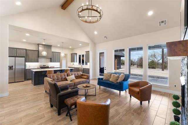 living area with visible vents, high vaulted ceiling, a chandelier, and light wood finished floors