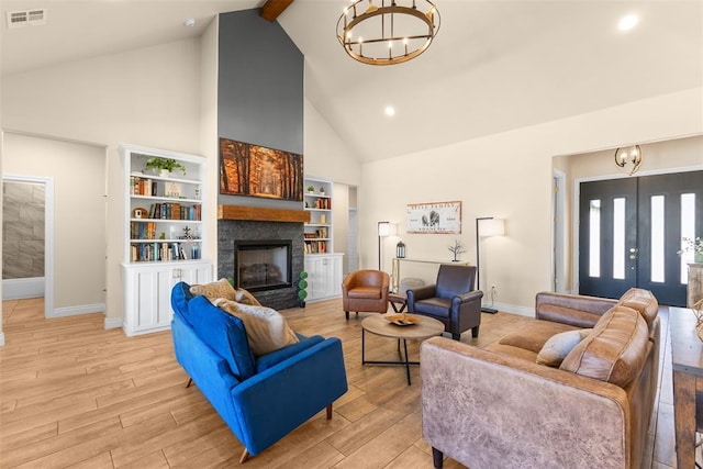 living room with light wood finished floors, visible vents, beam ceiling, a fireplace, and a notable chandelier