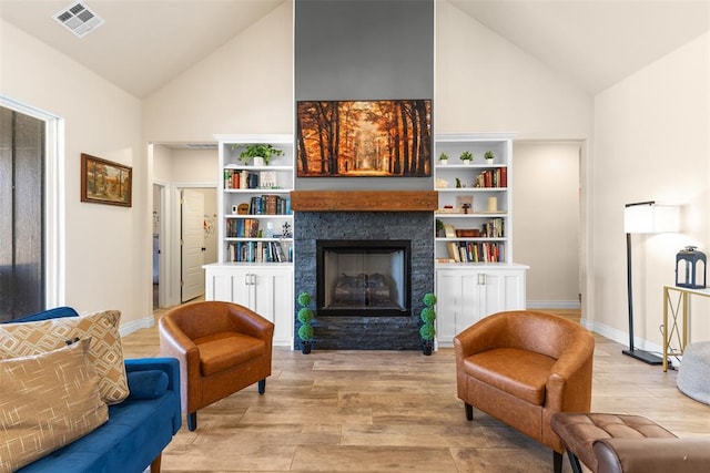 sitting room with wood finished floors, baseboards, visible vents, high vaulted ceiling, and a fireplace