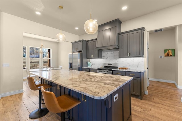 kitchen featuring light wood-type flooring, light stone countertops, tasteful backsplash, and stainless steel appliances