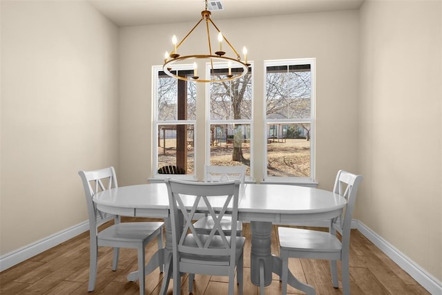 dining space with baseboards, an inviting chandelier, and wood finished floors