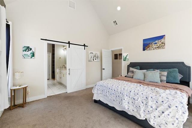 bedroom with visible vents, light colored carpet, high vaulted ceiling, and a barn door