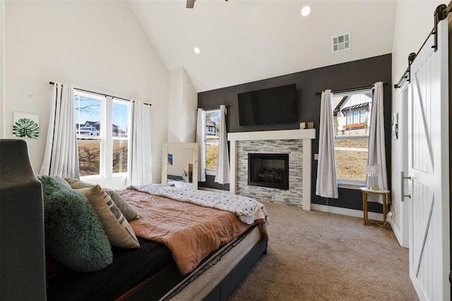 bedroom featuring visible vents, carpet, a barn door, a fireplace, and high vaulted ceiling