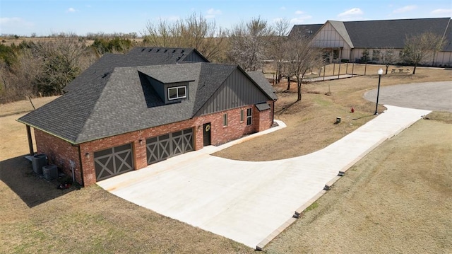 view of front of house with central air condition unit, concrete driveway, a shingled roof, a garage, and brick siding