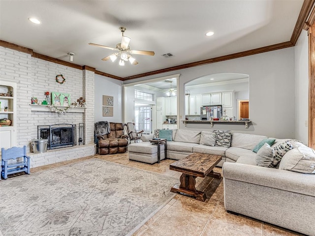 living area with visible vents, a brick fireplace, ceiling fan, ornamental molding, and light tile patterned floors