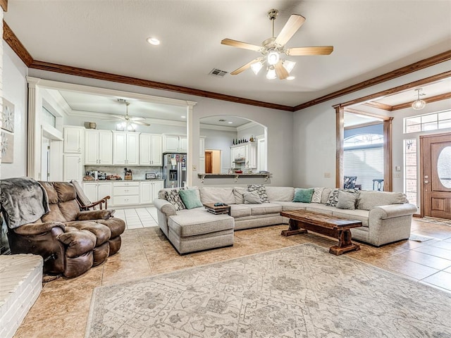 living room featuring visible vents, crown molding, ceiling fan, light tile patterned floors, and arched walkways