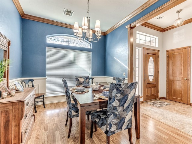 dining room featuring light wood-type flooring, visible vents, a notable chandelier, and crown molding