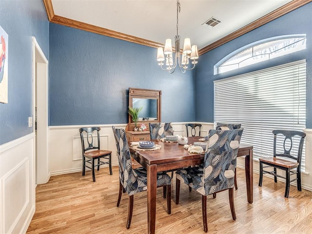 dining space with a chandelier, visible vents, light wood-type flooring, and crown molding