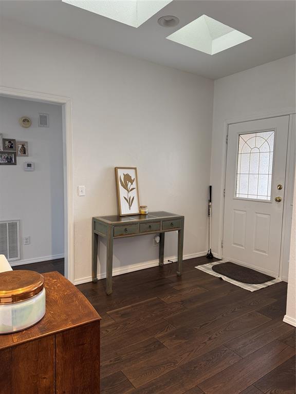 entryway with a skylight, wood finished floors, visible vents, and baseboards