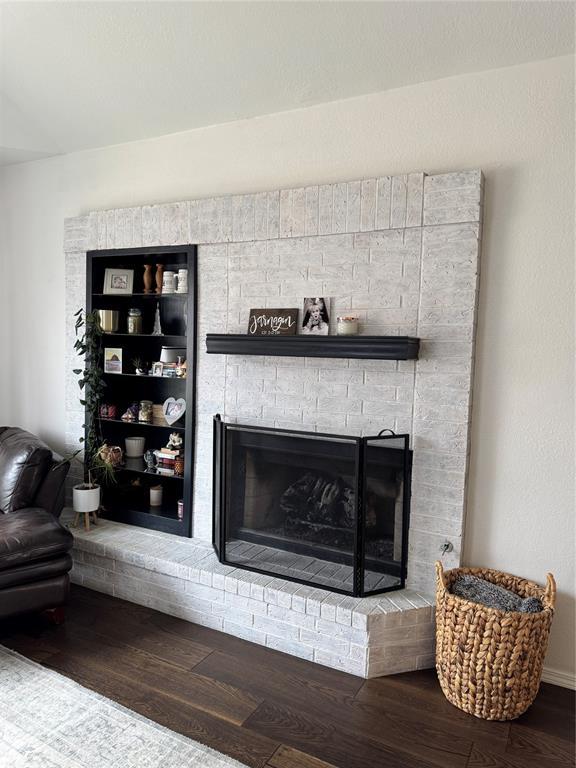 details featuring a brick fireplace and wood finished floors