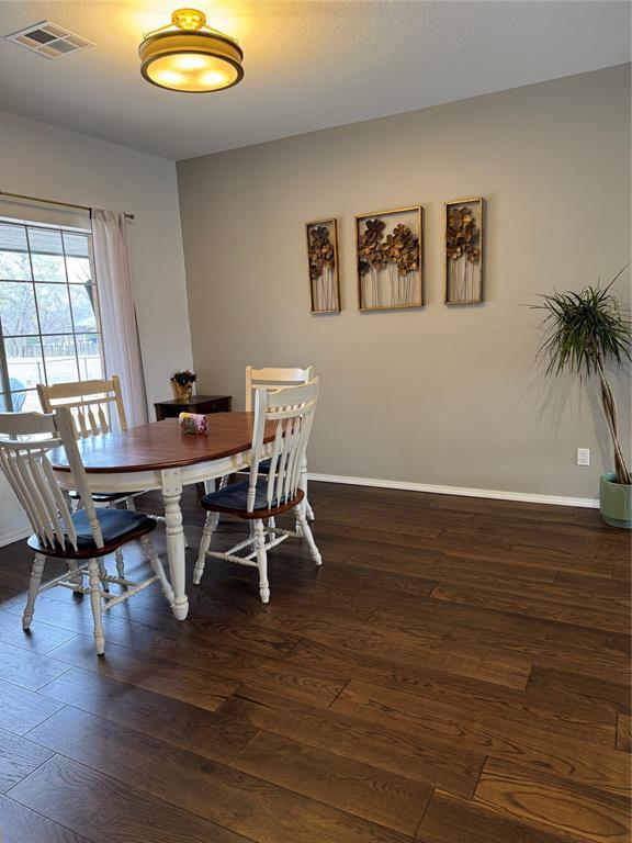 dining room featuring visible vents, baseboards, and dark wood-style flooring