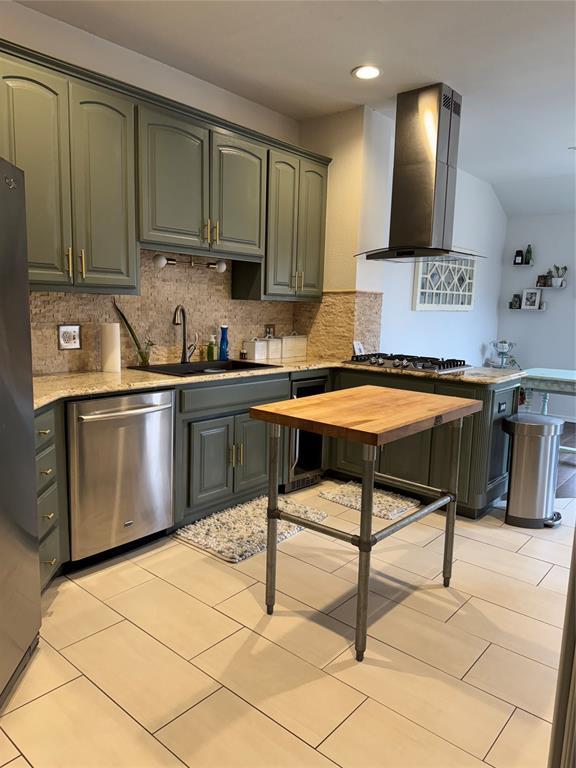 kitchen featuring beverage cooler, a sink, stainless steel appliances, wall chimney exhaust hood, and tasteful backsplash