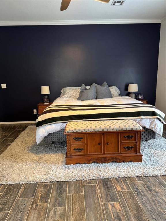 bedroom featuring a ceiling fan, wood finish floors, and ornamental molding