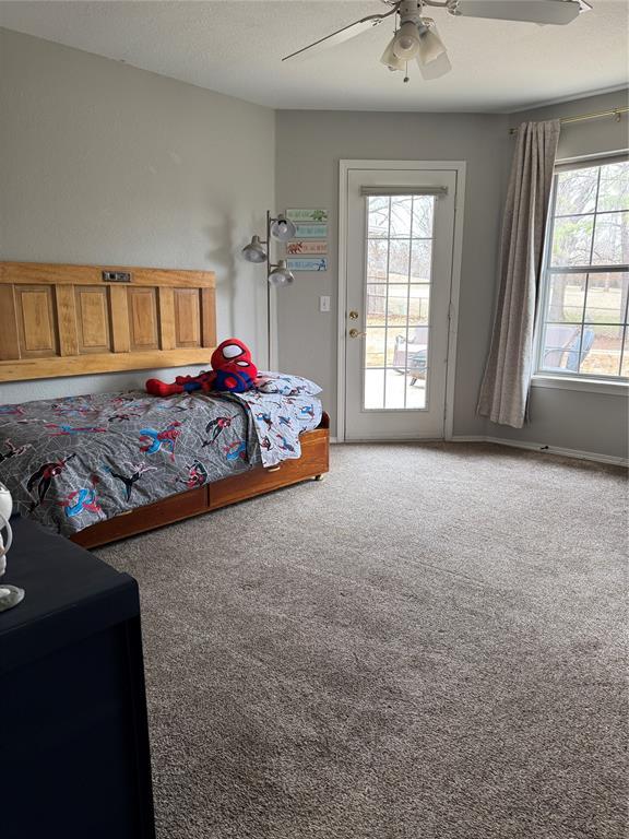 bedroom featuring baseboards, light carpet, ceiling fan, and access to outside