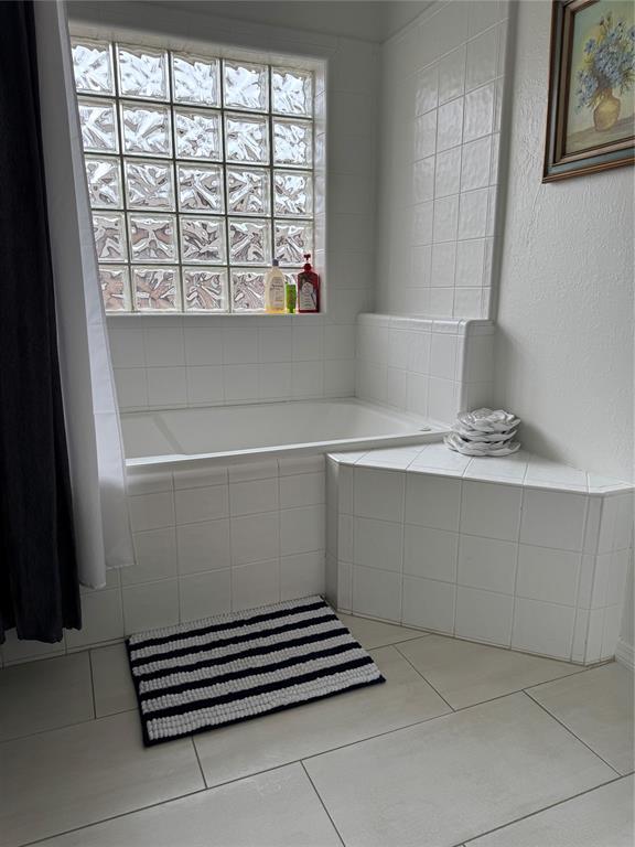 bathroom with a garden tub and tile patterned flooring