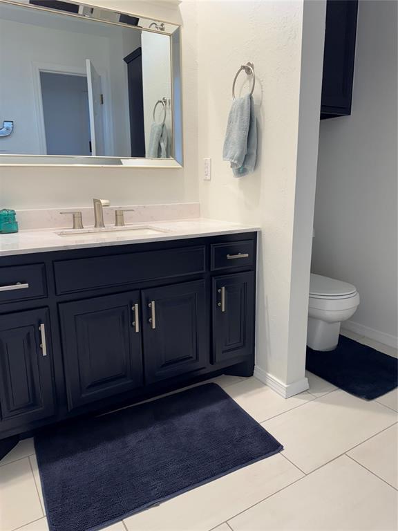 bathroom with baseboards, toilet, vanity, and tile patterned flooring