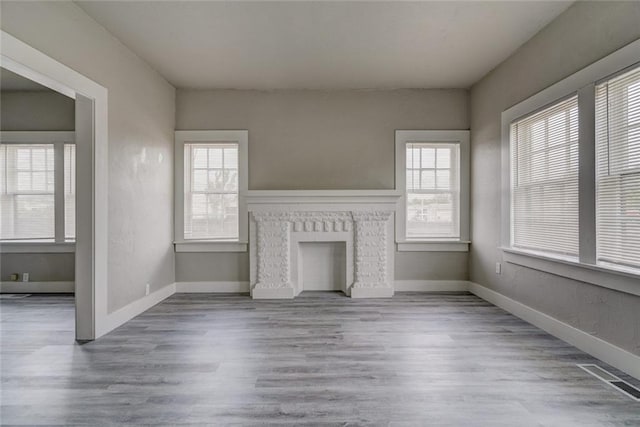 324 NW 24th St, Oklahoma City, OK 73103 - unfurnished living room with visible vents, baseboards, a brick fireplace, and wood finished floors