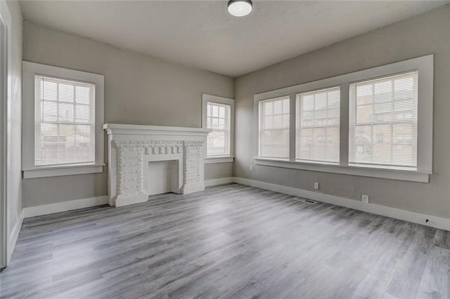324 NW 24th St, Oklahoma City, OK 73103 - unfurnished living room featuring a wealth of natural light, baseboards, wood finished floors, and a fireplace