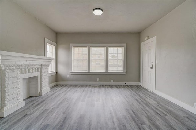 324 NW 24th St, Oklahoma City, OK 73103 - unfurnished living room with a brick fireplace, wood finished floors, and baseboards