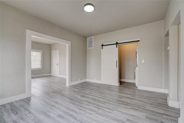 324 NW 24th St, Oklahoma City, OK 73103 - unfurnished room featuring visible vents, light wood-style flooring, baseboards, and a barn door