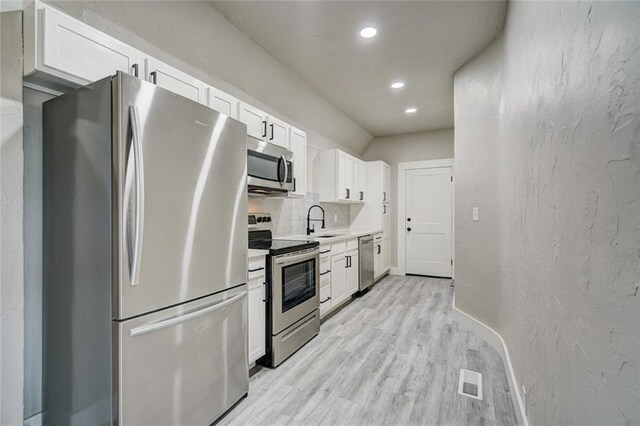 324 NW 24th St, Oklahoma City, OK 73103 - kitchen featuring light wood-type flooring, appliances with stainless steel finishes, a textured wall, white cabinets, and a sink