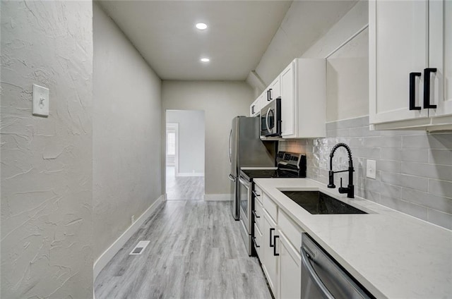 324 NW 24th St, Oklahoma City, OK 73103 - kitchen featuring visible vents, light wood finished floors, a sink, decorative backsplash, and stainless steel appliances