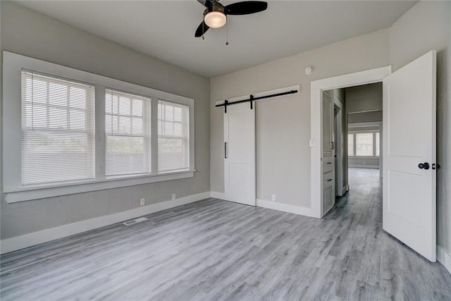 324 NW 24th St, Oklahoma City, OK 73103 - unfurnished bedroom with a ceiling fan, visible vents, baseboards, light wood-style flooring, and a barn door