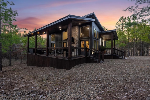 back of property at dusk featuring stone siding