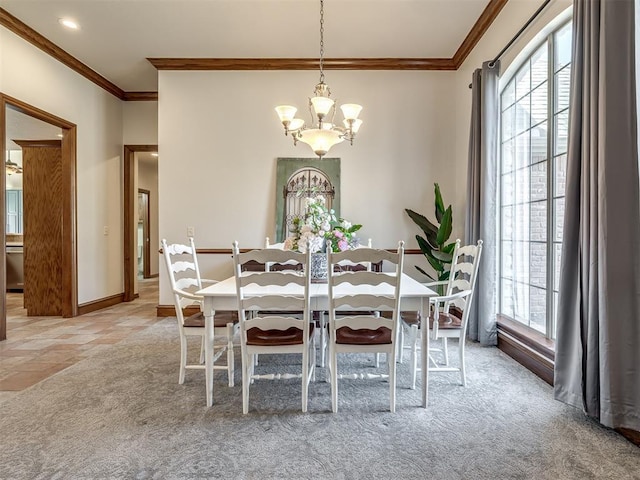 carpeted dining area with a chandelier, baseboards, and ornamental molding