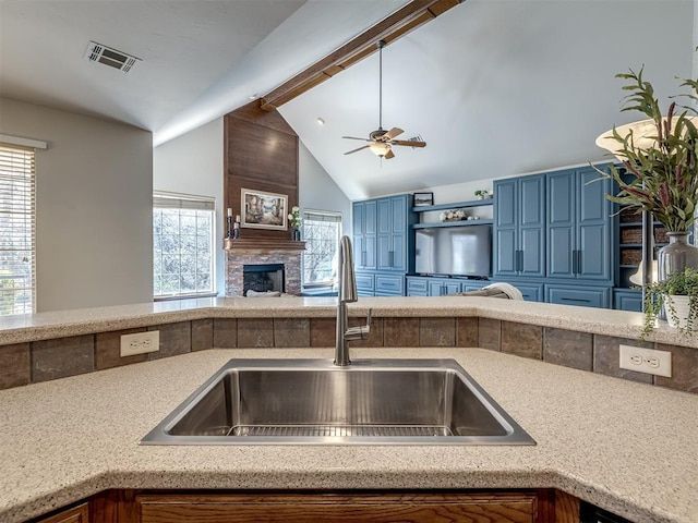 kitchen with a sink, visible vents, a large fireplace, and a wealth of natural light