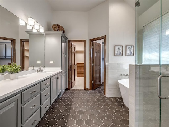 full bathroom with vanity, a stall shower, a freestanding bath, wainscoting, and tile walls