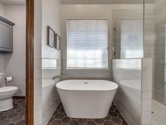 bathroom featuring a tile shower, toilet, tile patterned floors, and a freestanding bath