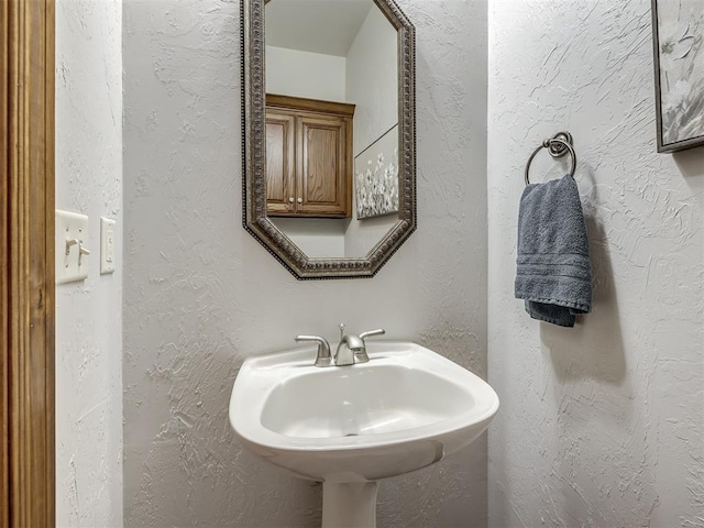 bathroom featuring a sink and a textured wall