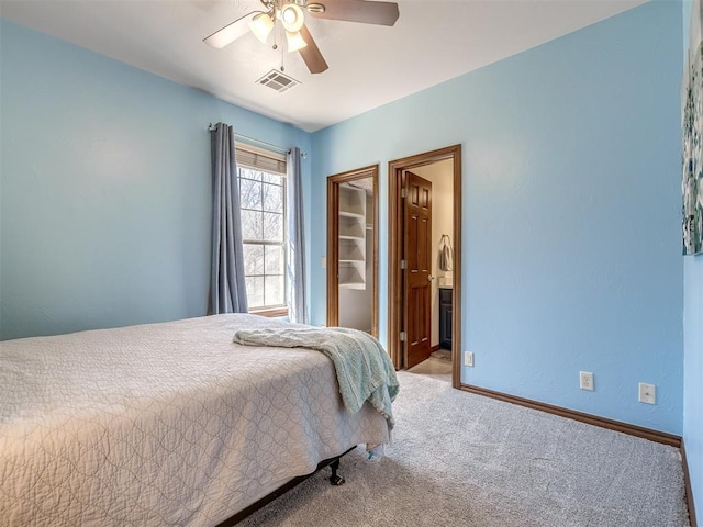 carpeted bedroom with connected bathroom, visible vents, baseboards, and ceiling fan