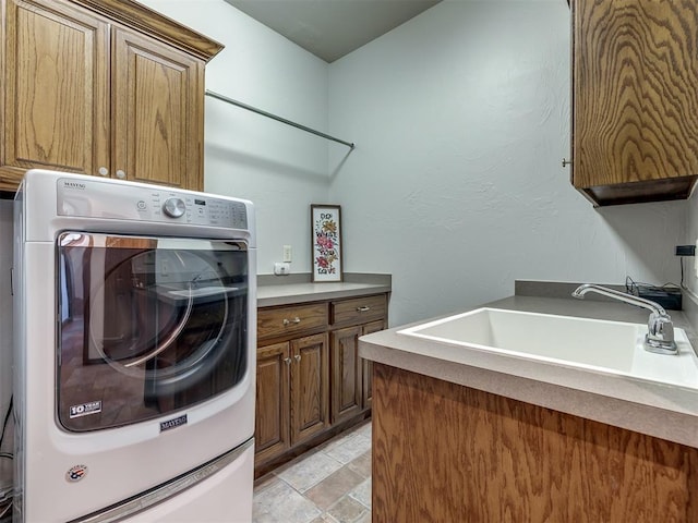 clothes washing area featuring cabinet space, washer / dryer, and a sink