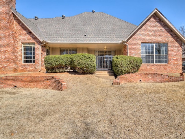 back of property with brick siding and roof with shingles