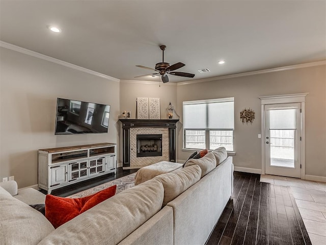 living area with visible vents, baseboards, ornamental molding, a fireplace, and wood finished floors