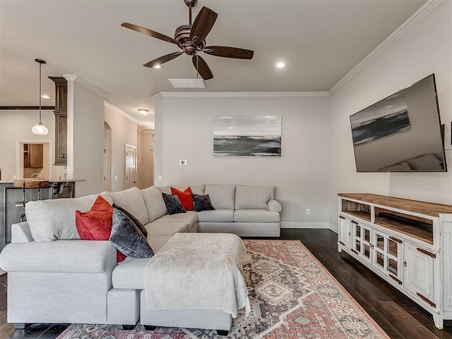 living area with dark wood-style floors, baseboards, visible vents, arched walkways, and ornamental molding