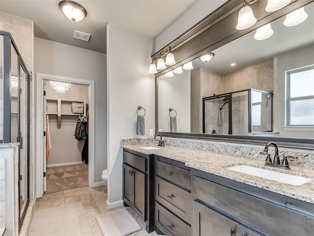 bathroom with visible vents, a shower stall, a walk in closet, and a sink