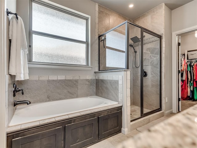 bathroom featuring a walk in closet, a garden tub, and a stall shower