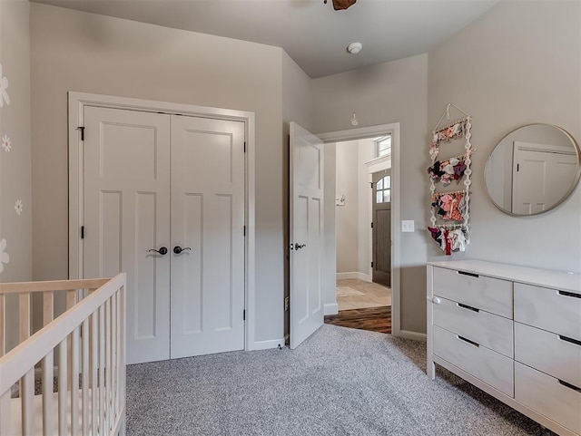 carpeted bedroom with a crib, baseboards, and a closet