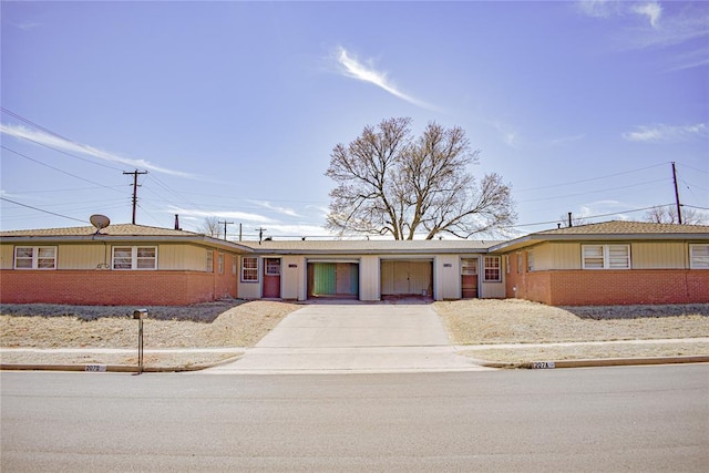 single story home featuring an attached garage, brick siding, and driveway