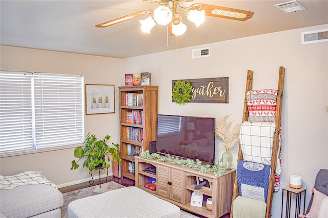 living area with visible vents, baseboards, and a ceiling fan