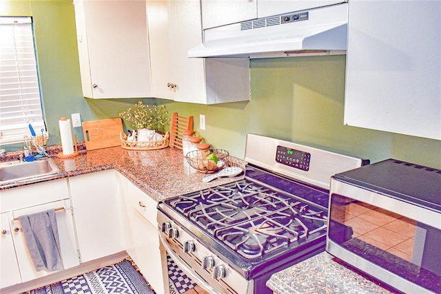 kitchen with tile patterned floors, under cabinet range hood, a sink, white cabinetry, and appliances with stainless steel finishes