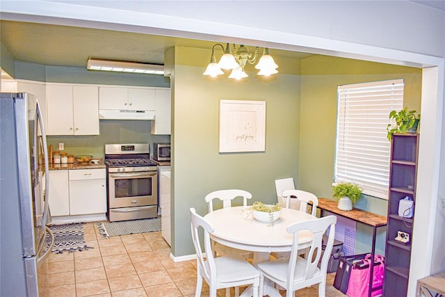 kitchen featuring a notable chandelier, under cabinet range hood, white cabinetry, appliances with stainless steel finishes, and light tile patterned flooring